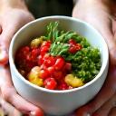 Bol de comida saludable con manos que lo sostienen, enfoque en la comida consciente