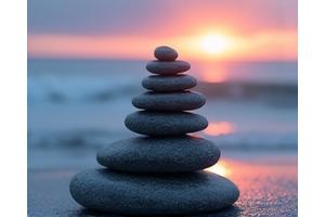 Piedras de equilibrio zen en una playa al atardecer, evocando calma y alivio de la ansiedad